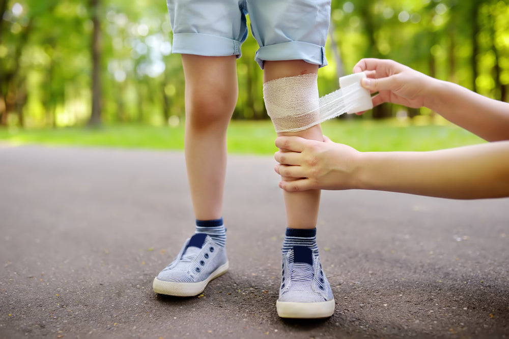 mom applying a bandage to her son's injured leg